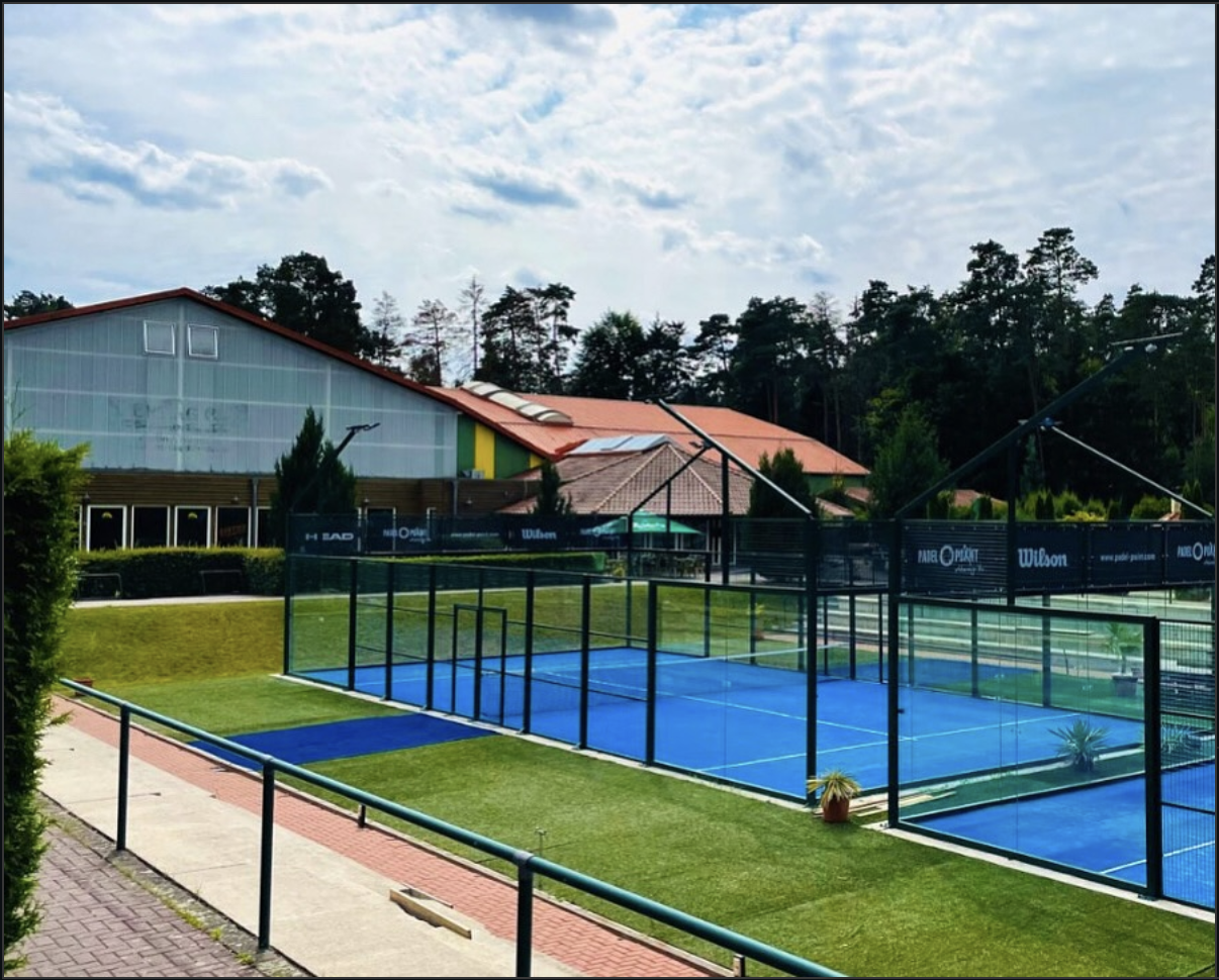 Pistas de pádel azules al aire libre frente al Sportzentrum Wandlitz con árboles al fondo